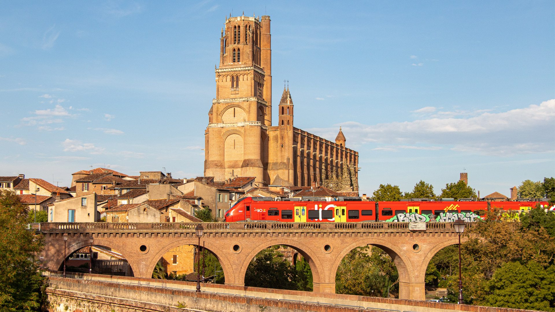 Com moure's per Albi - LIO serveix a la destinació d'Albi - passant el tren amb el teló de fons de la majestuosa catedral de Sainte Cécile