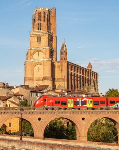 Zich verplaatsen in Albi - LIO bedient de bestemming Albi - de trein passeren tegen de achtergrond van de majestueuze Sainte Cécile-kathedraal